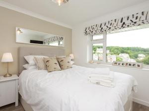 a white bedroom with a large bed and a window at Rockmount 1 in Salcombe