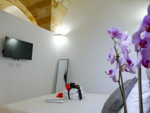 Una habitación con una mesa con espejo y flores moradas. en Leopardi B&B Brindisi Historic Center, en Brindisi