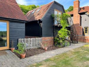 a black house with a white fence and some plants at Wysteria, North Lodge in Rusper