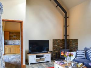a living room with a fireplace and a tv at Garden Cottage in Coldingham