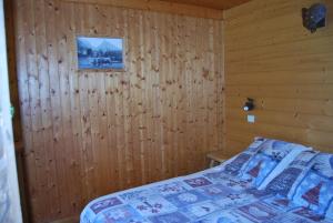 Un dormitorio con una cama con una pared de madera. en Vieille Bergerie 1, en Le Fernuy 7 fotos más