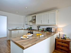 Una cocina con gabinetes blancos y una encimera de madera. en 3 Harbour View, en Newquay