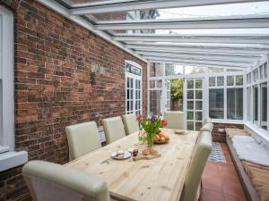 a dining room with a wooden table and a brick wall at Home Farm House in Dorrington