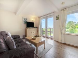 a living room with a couch and a tv at The Cottage in Fairlight