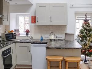 a kitchen with white cabinets and a christmas tree at The Old Barn - Uk40948 in Auchtermuchty