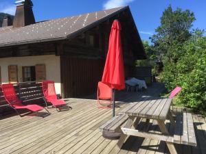 Una terraza con una mesa, una sombrilla roja y sillas. en Vieille Bergerie 3, en Le Fernuy