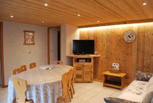 Una sala de estar con una mesa y un televisor. en Vieille Bergerie 3, en Le Fernuy