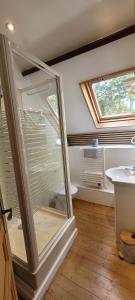 a bathroom with a glass shower door next to a sink at Maison de caractère - L'évasion forestière in Baguer-Pican