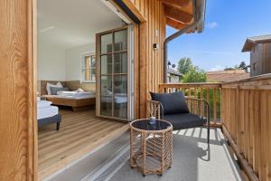a wooden balcony with a chair and a couch at BALANCED Münsing Ferienwohnungen Nähe Starnberger See in Münsing am Starnberger See