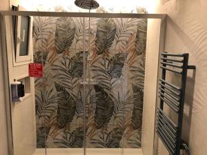 SuiteSweetGiovanna في تاورمينا: حمام بباب زجاجي مع جدارية من الأوراق