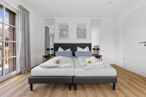 a bedroom with a large white bed with two pillows at BALANCED Münsing Ferienwohnungen Nähe Starnberger See in Münsing am Starnberger See