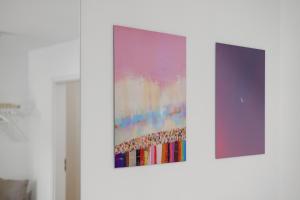 deux œuvres d'art accrochées à un mur blanc dans l'établissement BALANCED Münsing Apartments, vollausgestatte Ferienwohnungen Nähe Starnberger See, à Münsing