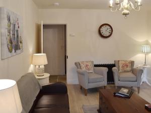a living room with a couch and two chairs and a clock at Starry Cottage in Bakewell