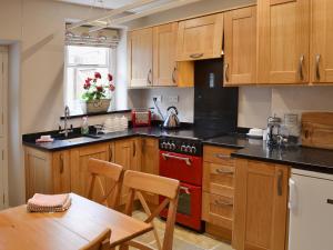 a kitchen with wooden cabinets and a red oven at Starry Cottage in Bakewell +4 photos
