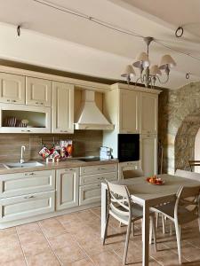 a kitchen with white cabinets and a table with chairs at La Dimora di Armida in Torricella Peligna