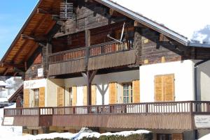 a wooden house with a balcony on the side of it at Vieille Bergerie 6 in Le Fernuy