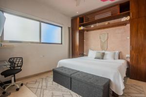 a bedroom with a bed and a chair and a window at Casa Bene Villas in Isla Mujeres