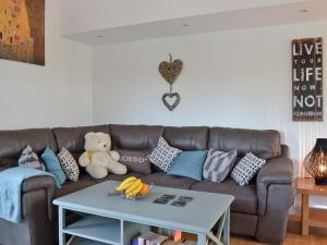 a living room with a brown couch and a table at Ty Isaf Cottage in Ffair-fâch