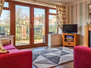 un salon avec un canapé et une télévision dans l'établissement Whitney Cottage, à Broadway