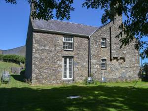 an old stone building with chairs in front of it at Bodwi Isaf in Llanengan