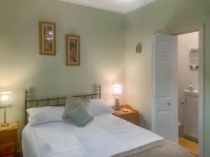 滨海戈尔斯顿The Yellow House的卧室配有一张白色床和一张桌子上的台灯