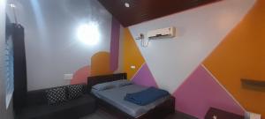 a small room with a bed and a colorful wall at Gokarna Beach Near Homestay RV in Gokarna