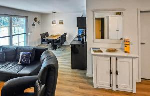 un salon avec un canapé noir et une cuisine dans l'établissement Ferienhaus Fuhlendorf, à Fuhlendorf