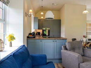 eine Küche mit blauen Schränken und 2 Stühlen in einem Zimmer in der Unterkunft Kingfisher Cottage in Kirkton of Airlie