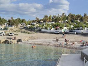 een groep mensen op een strand vlakbij het water bij Apartment in Šilo with Sea View Balcony in Šilo