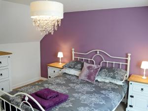 a bedroom with a bed with purple walls and a chandelier at Garden Cottage in Tain
