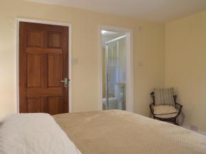 una camera con un letto, una sedia e una porta di Brookside Cottage a Forton