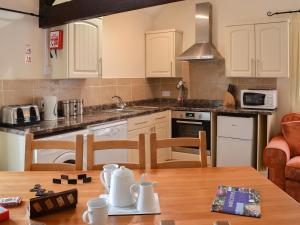 a kitchen with white cabinets and a wooden table at Granary - Ukc3373 in West Down