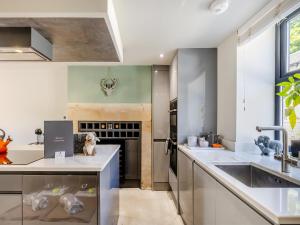 a kitchen with white counters and a sink at Squirrel Cottage in Glossop