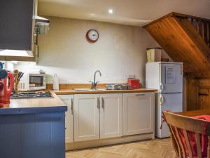 a kitchen with white cabinets and a white refrigerator at Felbridge Cottage in Bardon Mill