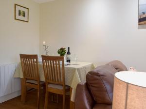 Un comedor con una mesa con sillas y una botella de vino. en Gardeners Lodge, en Pembroke