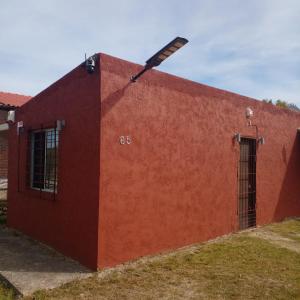 einem roten Backsteingebäude mit einer Tür und einem Fenster in der Unterkunft Casa en Barra del Chuy-Alvorada in Barra del Chuy