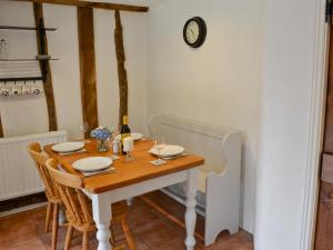 a dining room table with chairs and a clock on the wall at The Old Stables in Rickinghall