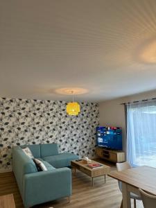 ein Wohnzimmer mit einem blauen Sofa und einem Fernseher in der Unterkunft Le Nid Des Grèves avec jacuzzi in Langueux