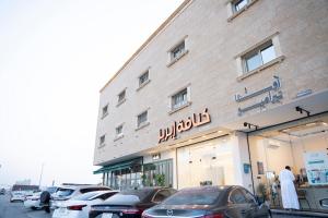 a building with cars parked in front of it at واحة الضيافة للشقق الفندقية Wahat Aldiyafah Hotel Apartments in Buraydah
