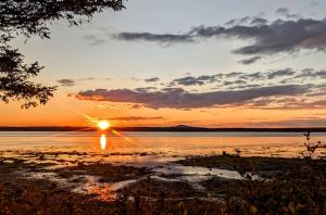 a sunset over a body of water with the sun setting at Tideside Beach House in Trenton