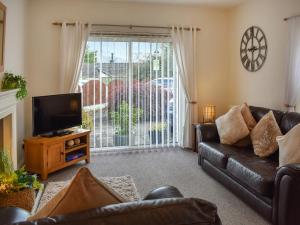 a living room with a black leather couch and a tv at No 8 Harney Peak in Portinscale