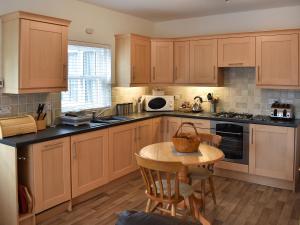 a kitchen with wooden cabinets and a small table at No 8 Harney Peak in Portinscale