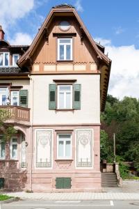 a pink house with green shutters and a window at Ruhestein Quartier - Charaktervolle Wohnung perfekt für Gruppen&Familien, ideale Lage, nahe Bhf und Iven, bestens geeignet für entspannte als auch akitve Aufenthalte in malerischer Umgebung in Baiersbronn