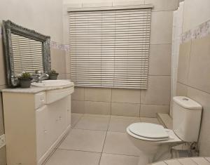 a white bathroom with a toilet and a sink at Chandané Guesthouse in Thabazimbi