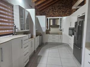 a kitchen with white cabinets and a brick wall at Chandané Guesthouse in Thabazimbi