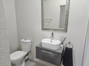 a white bathroom with a toilet and a sink at Chandané Guesthouse in Thabazimbi