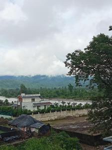 a view of a river with a building and a tree at Krishna's Paradise in Rishīkesh