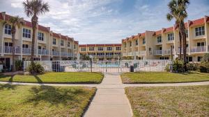 un gran edificio con palmeras y una pasarela en Pier Point Ocean View Unit D-52, en St. Augustine Beach