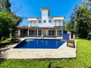 a house with a swimming pool in the yard at Casa Verão Guaratuba - Bertioga in Bertioga