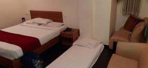 a small bedroom with two beds and a couch at Hotel Sree in Tiruchchirāppalli +3 photos